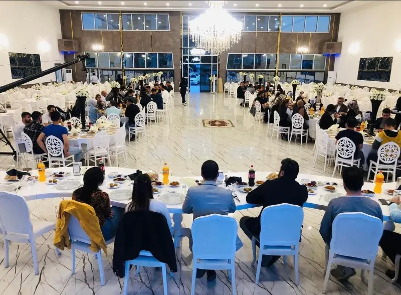 General view of the Gala Hall with tables, white chairs and a chandelier