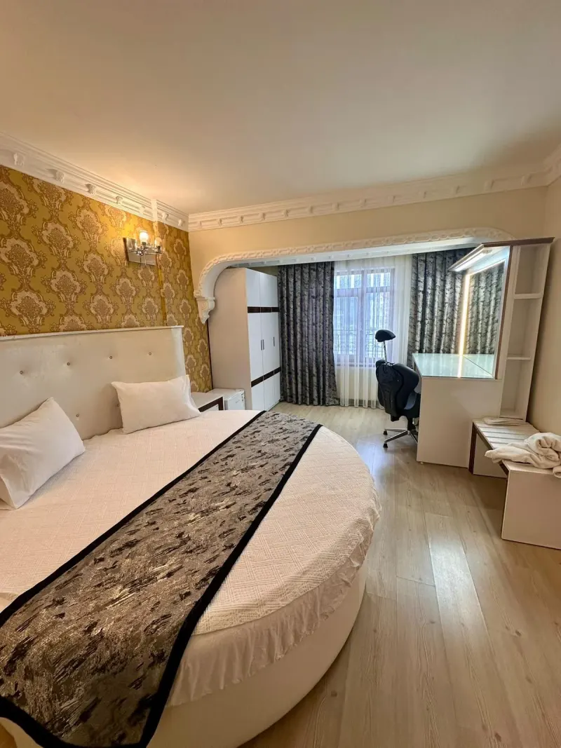 King Suite: round white bed, gold patterned wallpaper and a desk