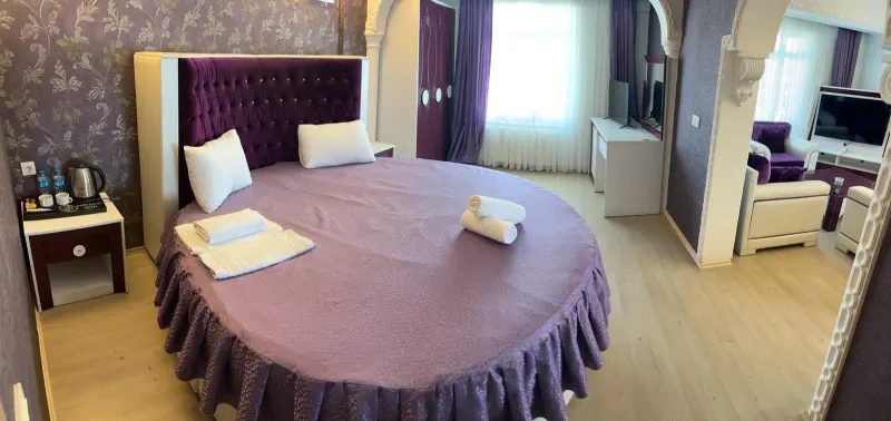 Suite Room: round bed with a purple cover, a purple tufted headboard and a TV