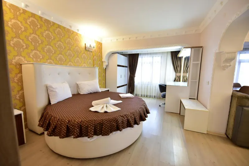 Suite Room: round bed with a brown cover and gold patterned wallpaper
